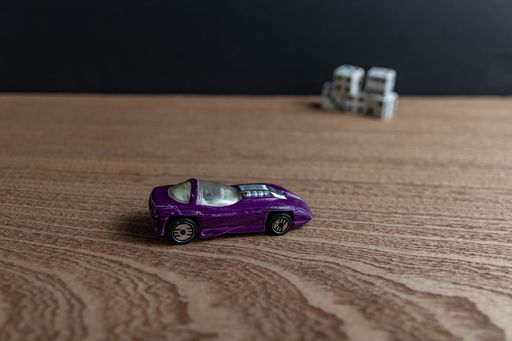 A selective focus shot of a toy sports car on a wooden surface