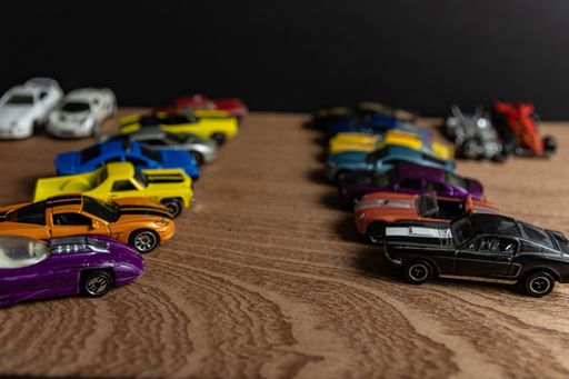 A selective focus shot of toy sports cars in a line on a wooden surface