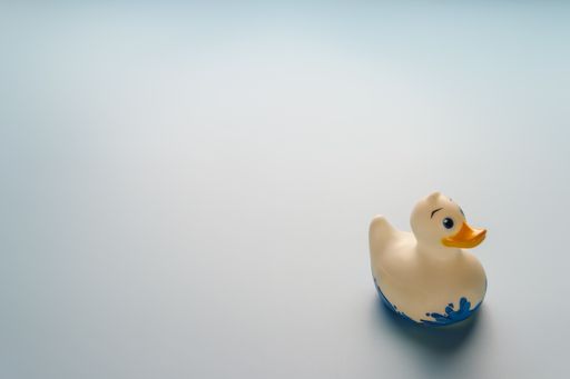 A closeup shot of a rubber duck on a light blue background