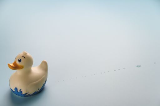 A closeup shot of a rubber duck on a light blue background