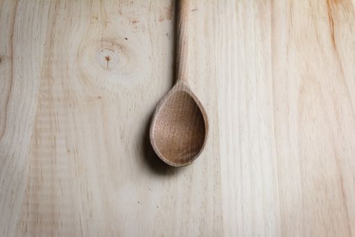 A high angle shot of a wooden spoon on a wooden table