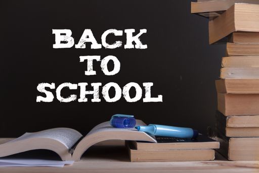 A "Back to school" writing and books, paper, pencil, highlighter marker on a wooden table
