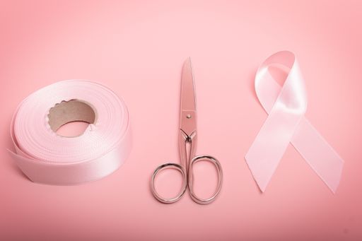 The materials to make a pink bow: a skein of pink tape, scissors, and the bow on a pink background.