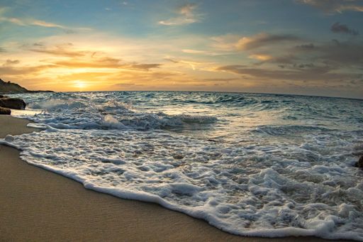 A beautiful view of foamy waves washing the sandy coast