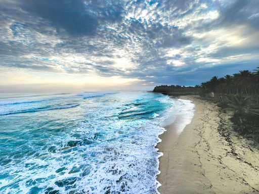 A beautiful view of foamy waves washing the sandy coast of a tropical islan