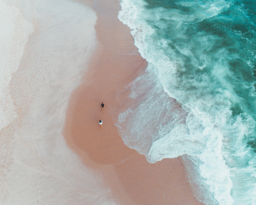 An overhead shot of people enjoying a sunny day at a sandy beach near beautiful waves of the sea