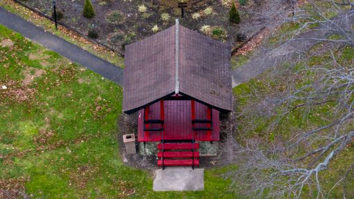 An aerial view of a red hut in an empty park on a cloudy day in autumn