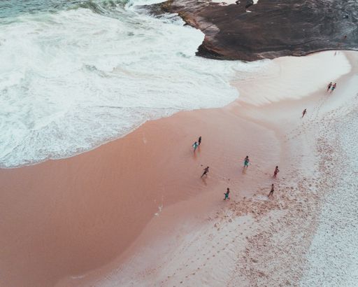 An overhead shot of people enjoying a sunny day at a sandy beach near beautiful waves of the sea