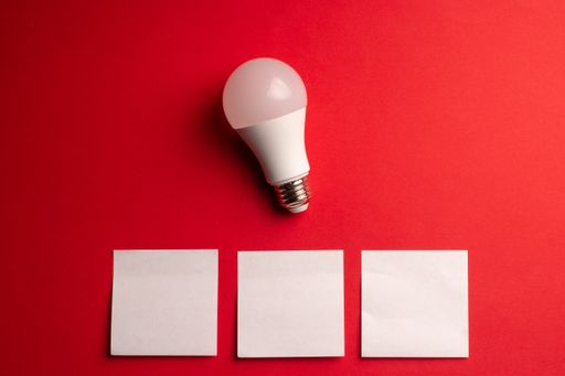 A top view of an electric light bulb  with white papers on a red background