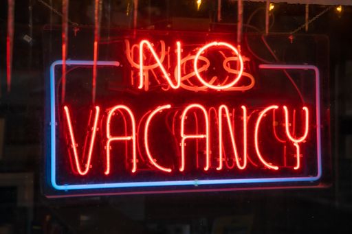 A closeup of the lighted signage saying "NO VACANCY" on the glass window