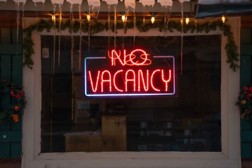 A closeup of the lighted signage saying "NO VACANCY" on the glass window