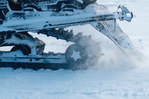 A closeup shot of the snowmobile wheels while splashing snow around
