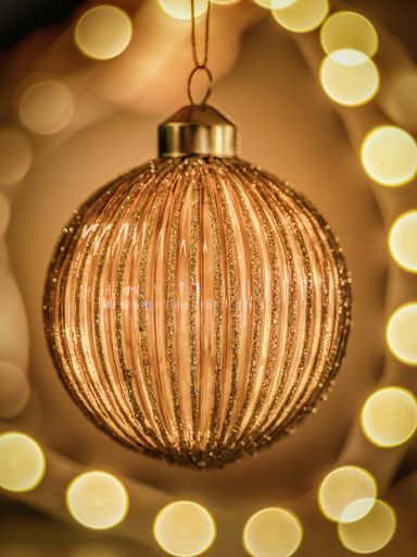 A vertical shot of beautiful Christmas tree ball with glitter on abstract background perfect wallpaper
