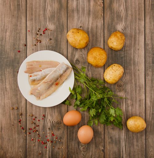A top view of vegetables, eggs, and fish on a table