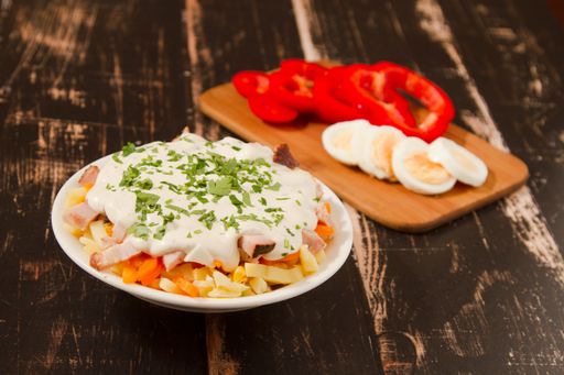A closeup shot of a chicken salad and sliced peppers and eggs on a board