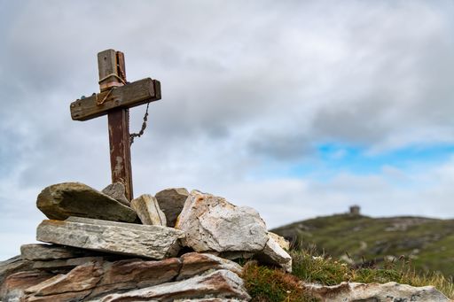 A wooden cross prominently displayed on top of a rocky mountain landscape
