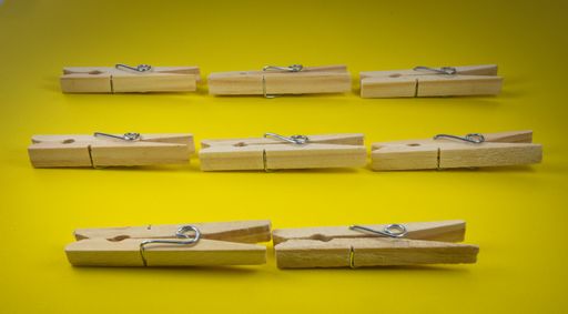 A closeup shot of wooden clothespins on a yellow background