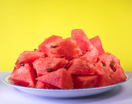 A closeup shot of fresh sliced watermelon on a plate against a yellow background