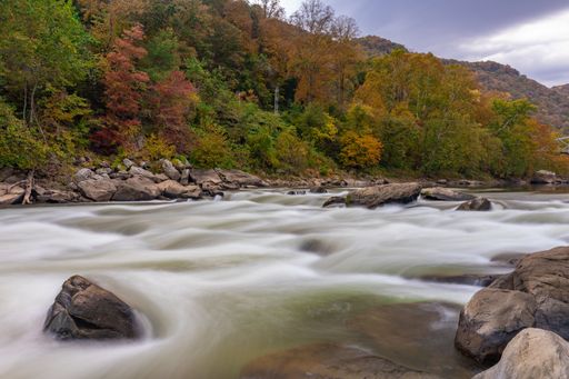 A stunning landscape of New River in Gorge National Park with autumn trees in the background