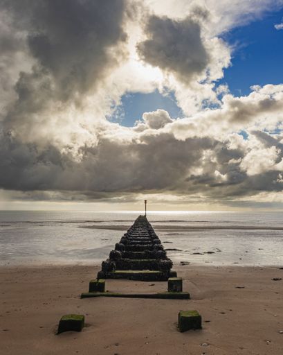 An aerial view of path on sandy beach in sea during sunset