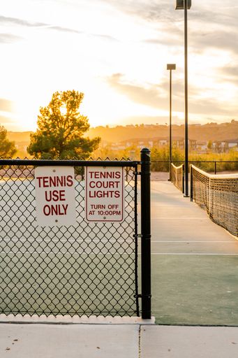 A vertical shot of a tennis court fence during sunset hour