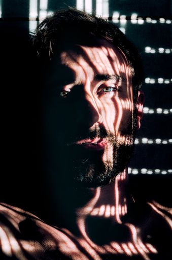 A young man look at camera between lights and shadows