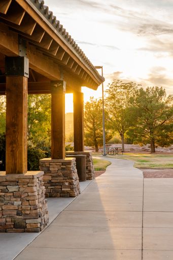 A vertical shot of a walkway next to wooden and brick poles during sunset with a park in the background