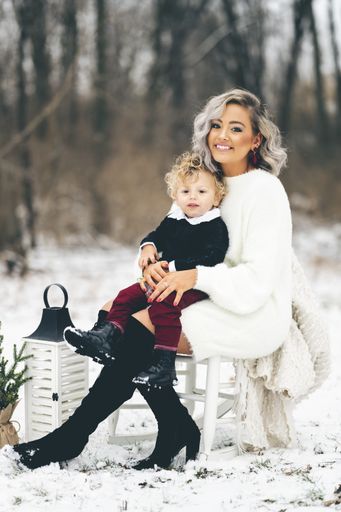 A young mother sitting on a chair outdoors with her son on her lap