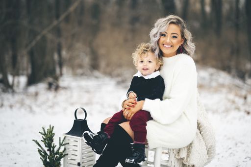 A young mother sitting on a chair outdoors with her son on her lap