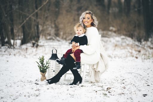 A young mother sitting on a chair outdoors with her son on her lap