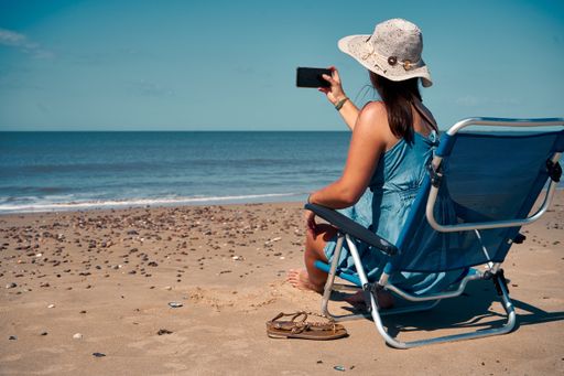 A backshot of a young female sitting in bed and taking the picture of the se