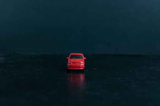 A selective focus shot of a red toy car on a black surface