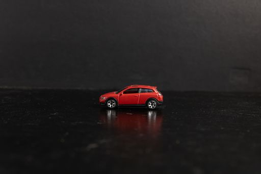 A selective focus shot of a red toy car on a black surface