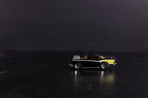 A selective focus shot of a black and yellow toy sports car on a black surface