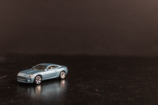 A selective focus shot of a light blue toy car on a black surface