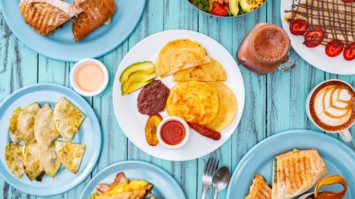 An overhead shot of a table full of delicious food and drinks on a blue table