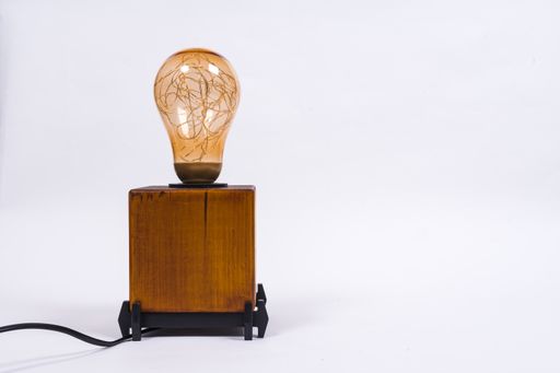 A closeup shot of a levitating table lamp on a wooden box on a white background