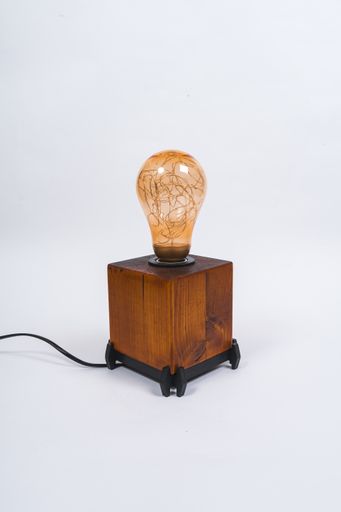 A vertical shot of a levitating table lamp on a wooden box on a white background