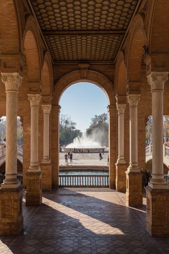 Vertical shot of the fountain in Plaza de Espana framed between two rows of columns
