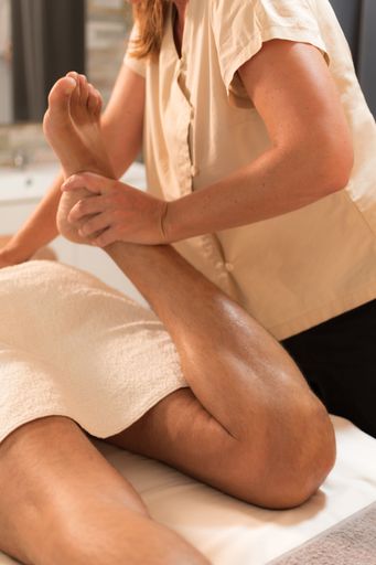 rear view of a man's leg receiving muscle stretching for a leg massage
