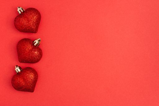 A top view of red heart shape balls on a red background