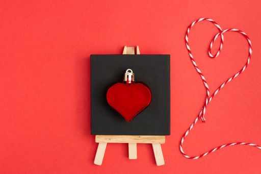 A top view of a red heart shape ball on a blackboard with heart thread on a red background