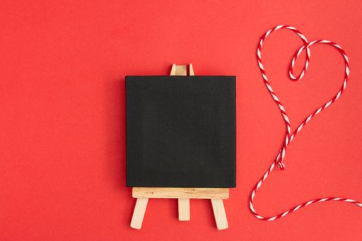 A top view of a blackboard with heart thread on a red background