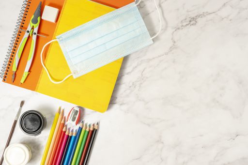 A sanitary mask, colored pencils, notebooks, compass, brush, rubb on a marble table