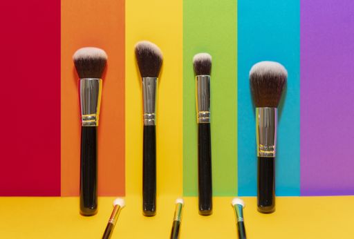 A closeup shot of makeup brushes on LGBT movement flag colors background