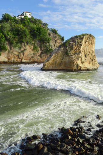 A vertical shot of beautiful rocks and cliffs by the ocean under the blue sky