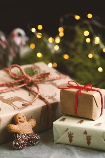 Three gift boxes with eco paper and burlap thread and a gingerbread cookie on a bokeh background