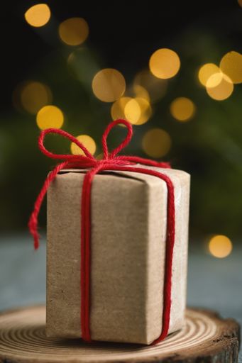 A wrapped gift with eco paper and a red bow on a bokeh background