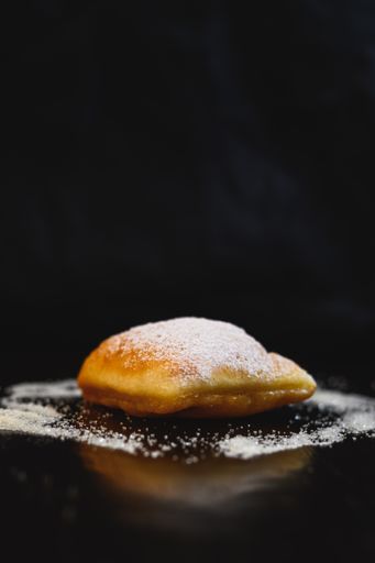 A vertical shot of homemade cakes with sweet powder on a black background