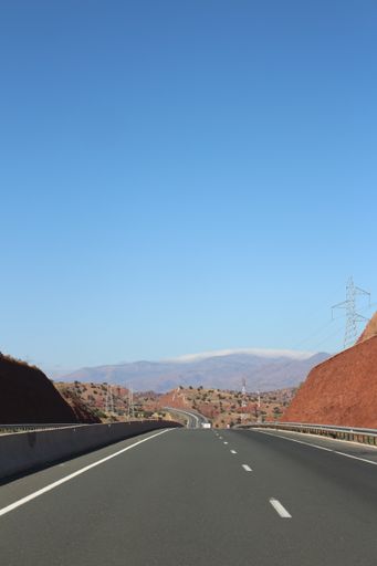 A vertical shot of a curvy road going through a dry landscape under a clear sky